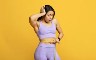 Person measuring waist to track body composition during Ozempic weight loss journey